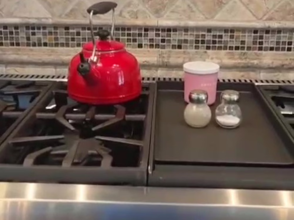 Stove and backsplash after Kitchen Deep Cleaning, featuring a red kettle and organized condiments on a spotless cooktop.