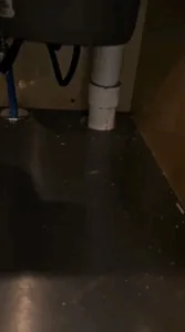 Complete Kitchen Cleaning: Before cleaning – a dirty under-sink area with exposed plumbing and debris on the countertop.