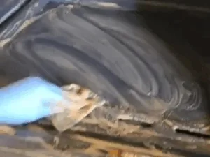 Stove Cleaning Process: A person scrubbing a stovetop with a cleaning cloth, removing built-up grease and grime.
