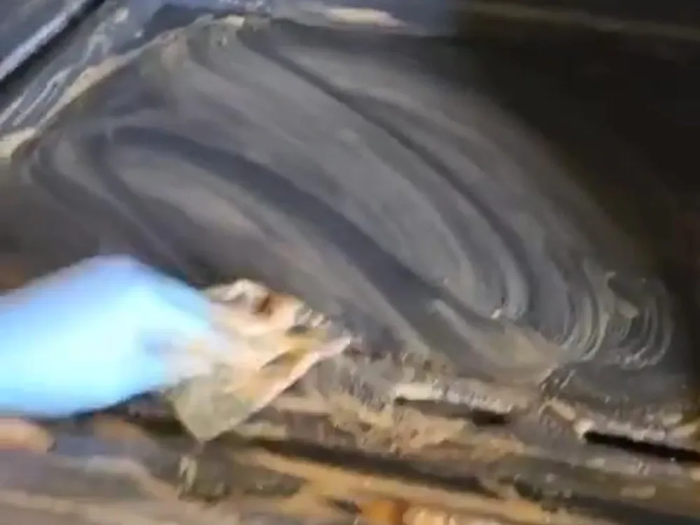 Stove Cleaning Process: A person scrubbing a stovetop with a cleaning cloth, removing built-up grease and grime.