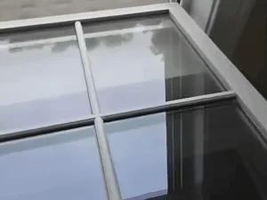 Window cleaning process viewed from inside showing open window and outdoor work.
