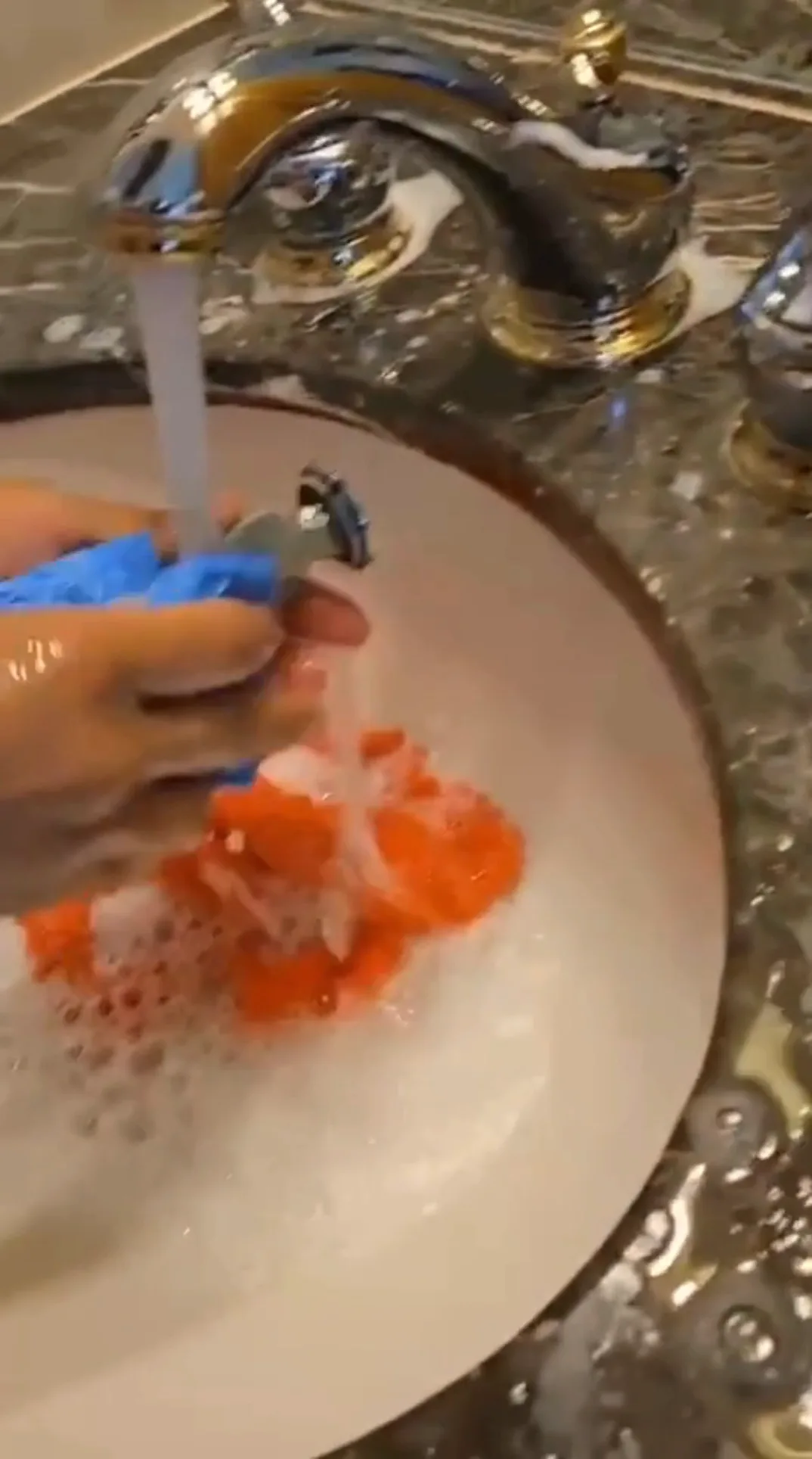 Hands scrubbing bathroom faucet with sponge and soap during Effective Bathroom Cleaning.