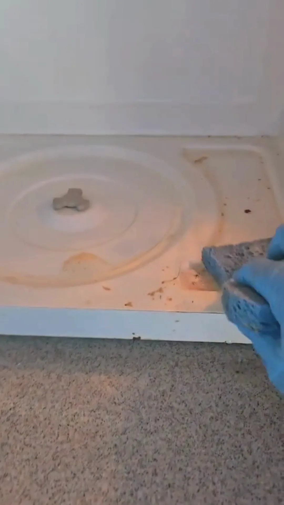 Microwave interior cleaning in progress with sponge removing debris